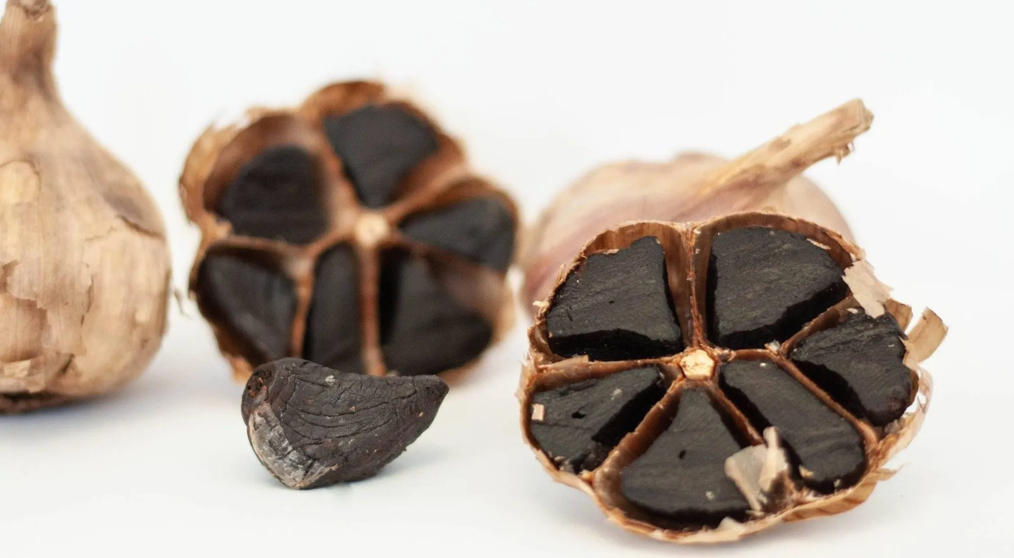 Halved bulbs of Kipp black garlic showing soft black cloves